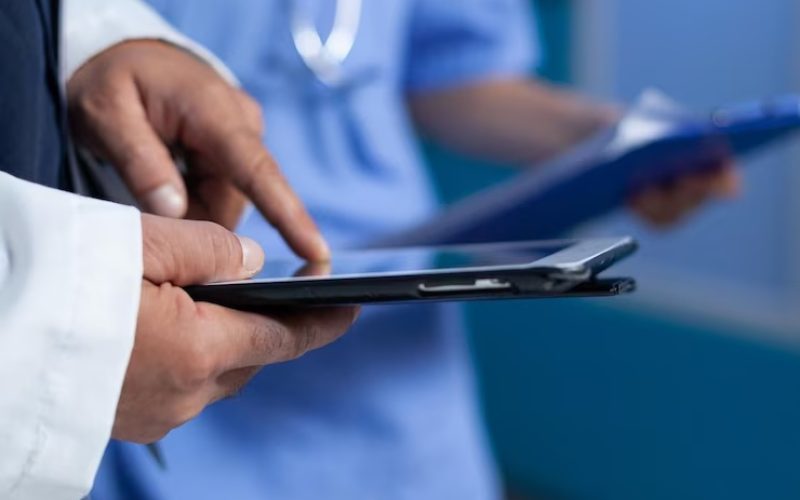 cerca-medico-apuntando-pantalla-tableta-practica-medica-trabajando-tarde-medico-que-usa-dispositivo-